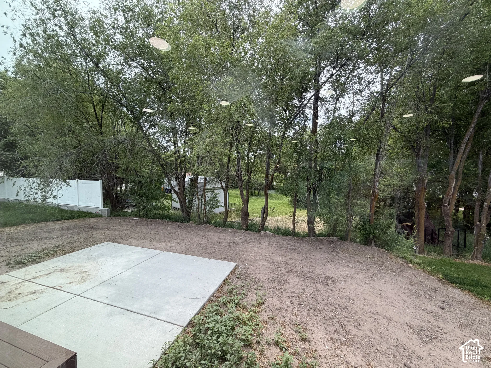 Concrete patio, white vinyl privacy fencing, and mature trees