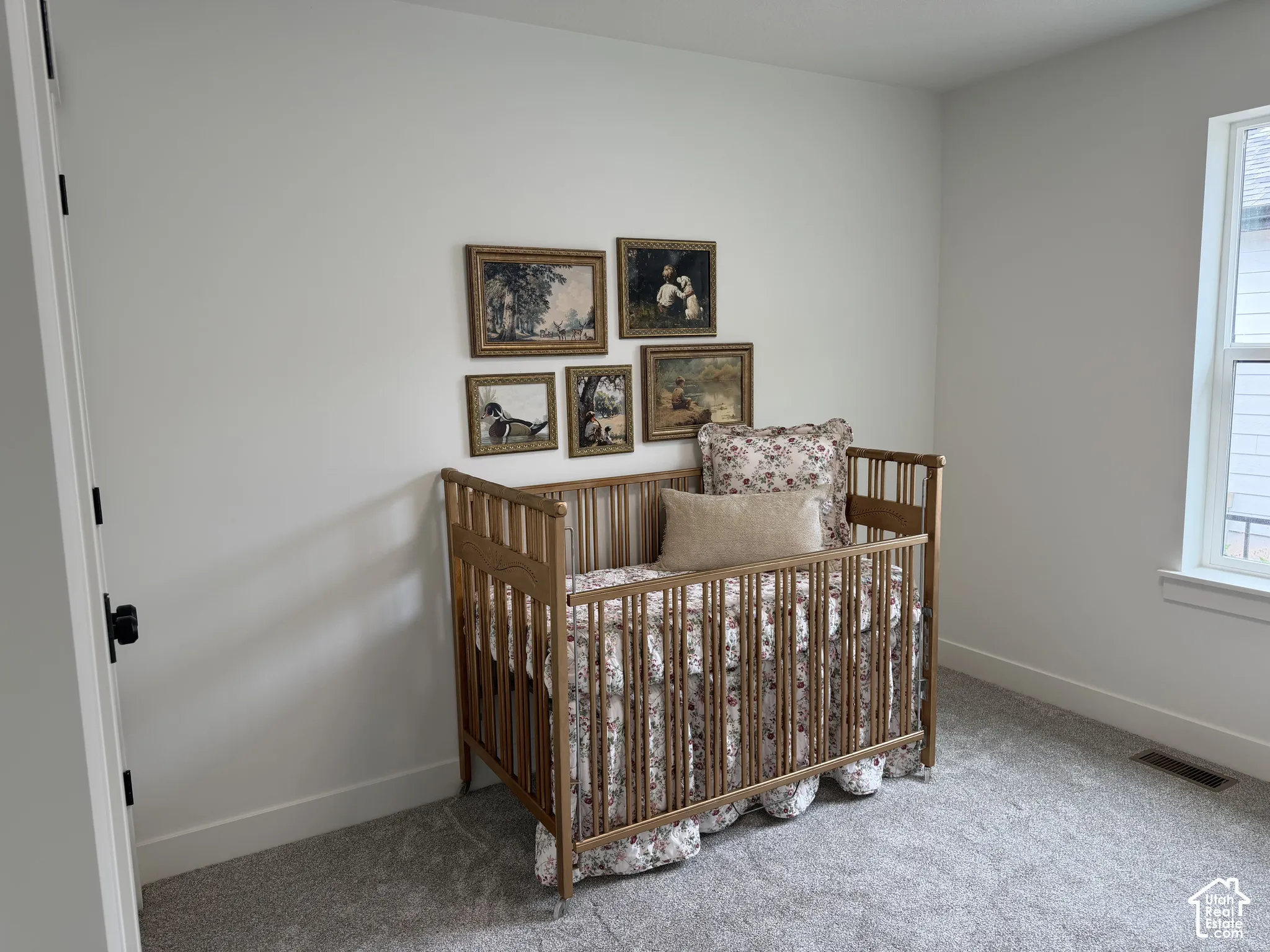 Neutral-toned interior space featuring light-colored wall paint, plush carpeting, and a single-pane window