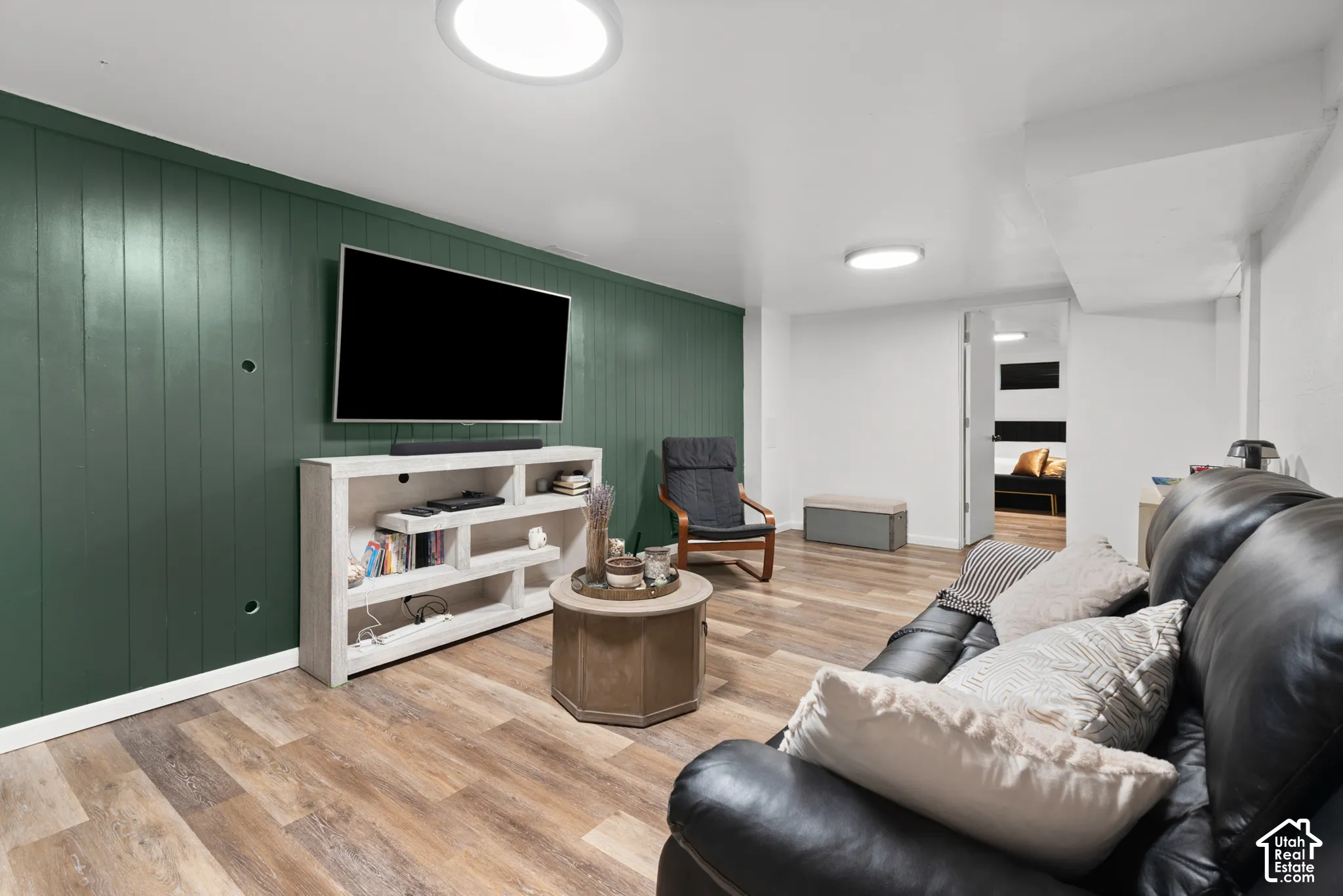 Interior room featuring green vertical wood-plank paneling, wood-finish flooring, and dual flush-mount ceiling light fixtures