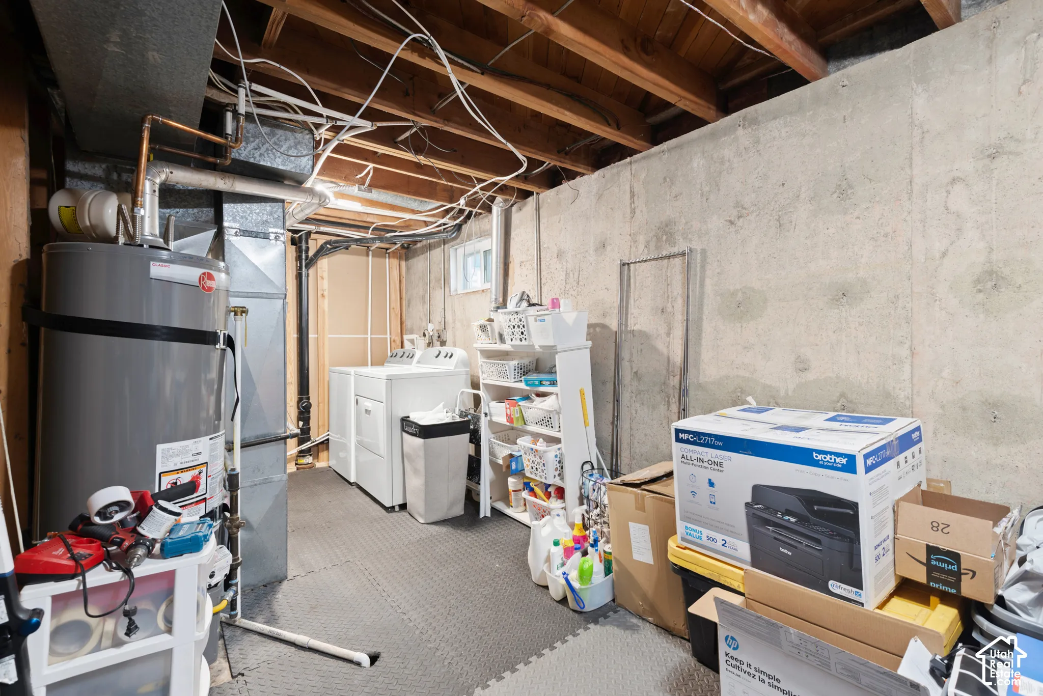 Unfinished basement utility area featuring exposed wood joist ceilings, poured concrete walls, and dedicated laundry hookups
