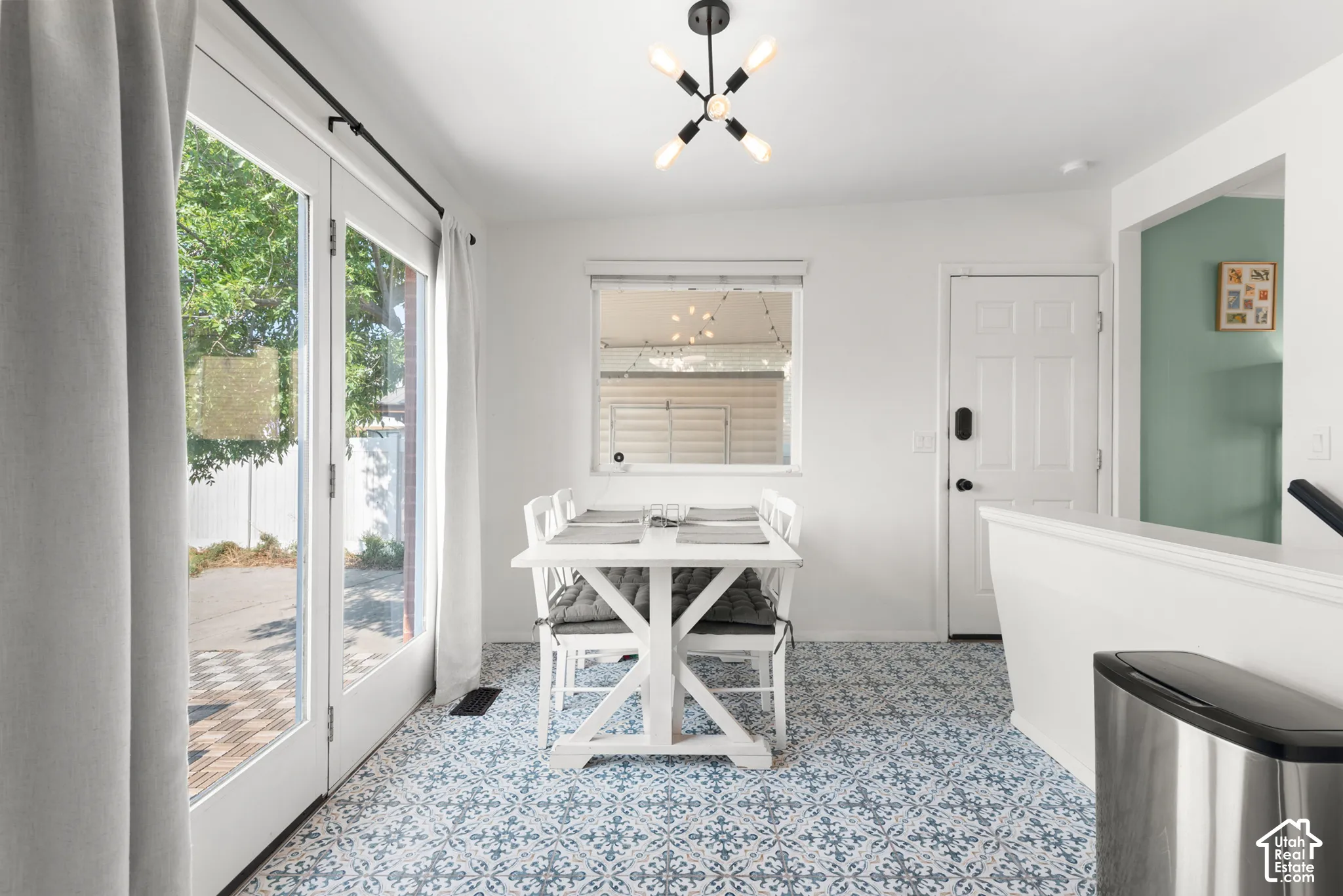 Patterned tile flooring, multi-light geometric ceiling fixture, and dual-paned glass door with natural light