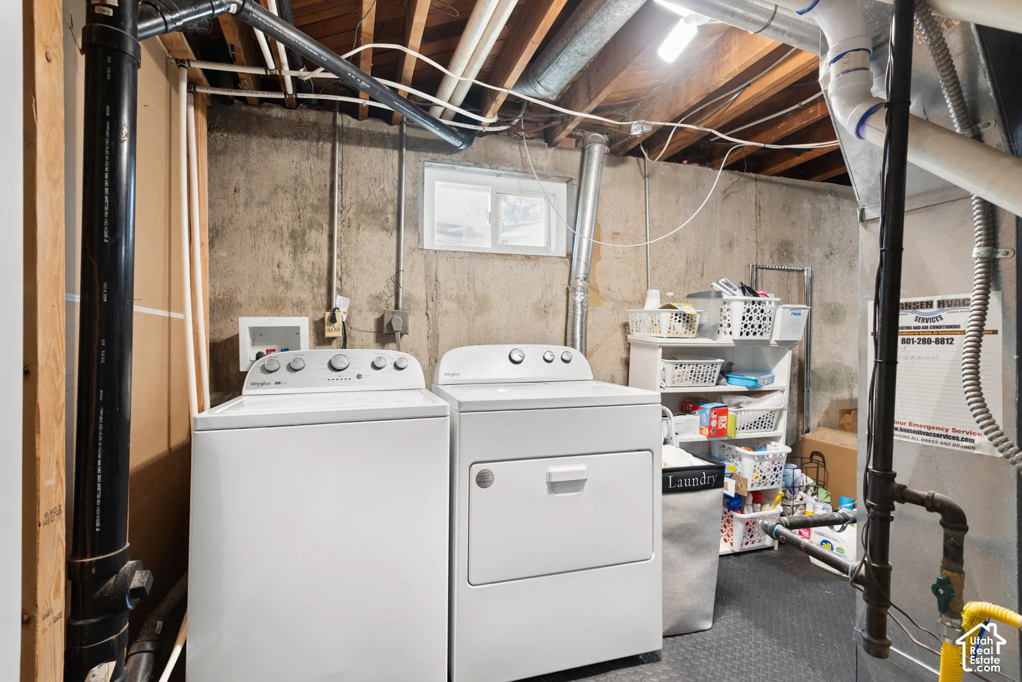 Utility area featuring exposed ceiling joists, concrete foundation walls, a window for natural light, and dedicated laundry hookups