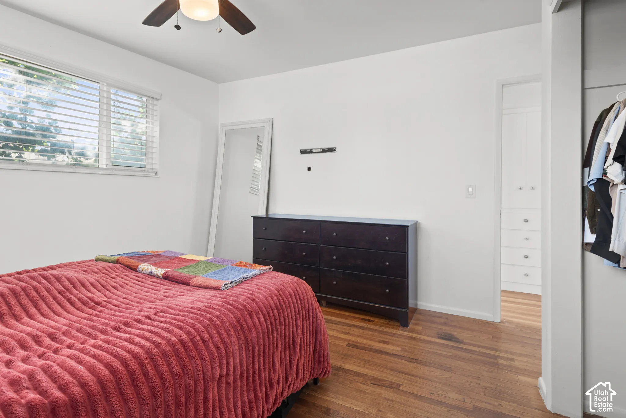 Wood-finish flooring, horizontal window blinds, ceiling fan with integrated lighting, and built-in white cabinetry with drawer hardware