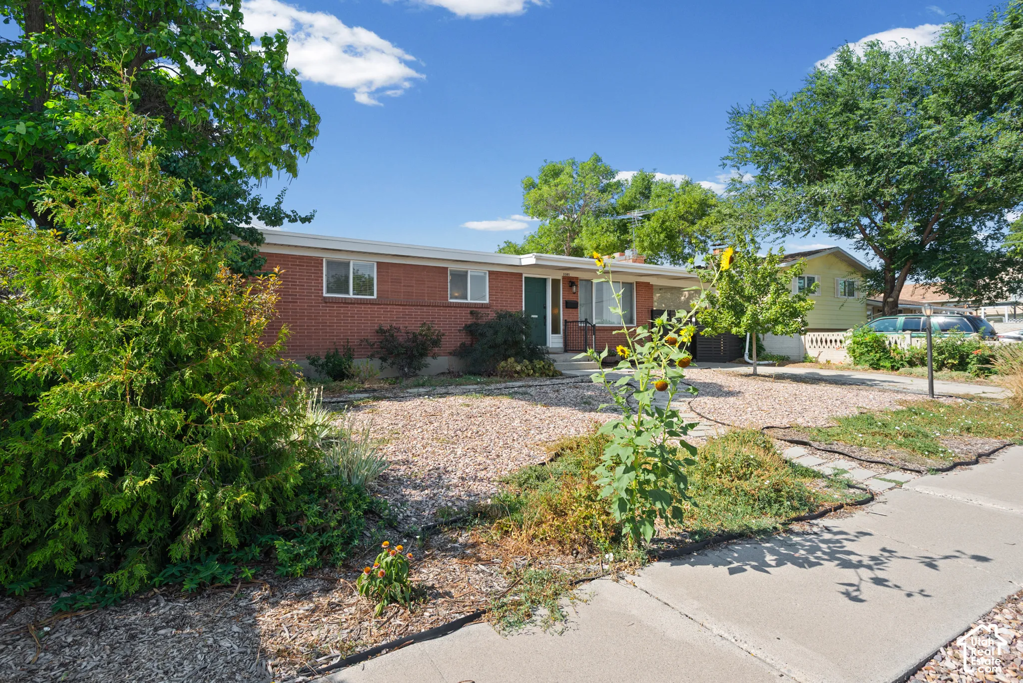 Single-story brick exterior featuring a low-pitch roofline, double-pane windows, and stone-mulched front landscaping