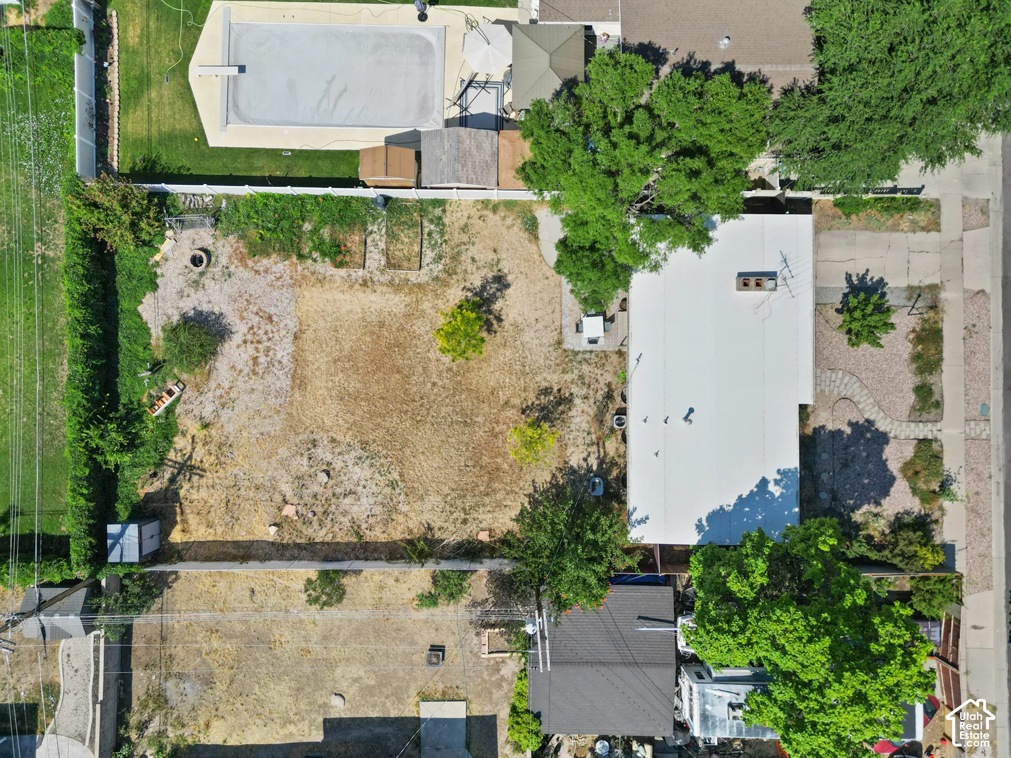 Expansive lot featuring an inground swimming pool, concrete patio, mature trees, and perimeter fencing