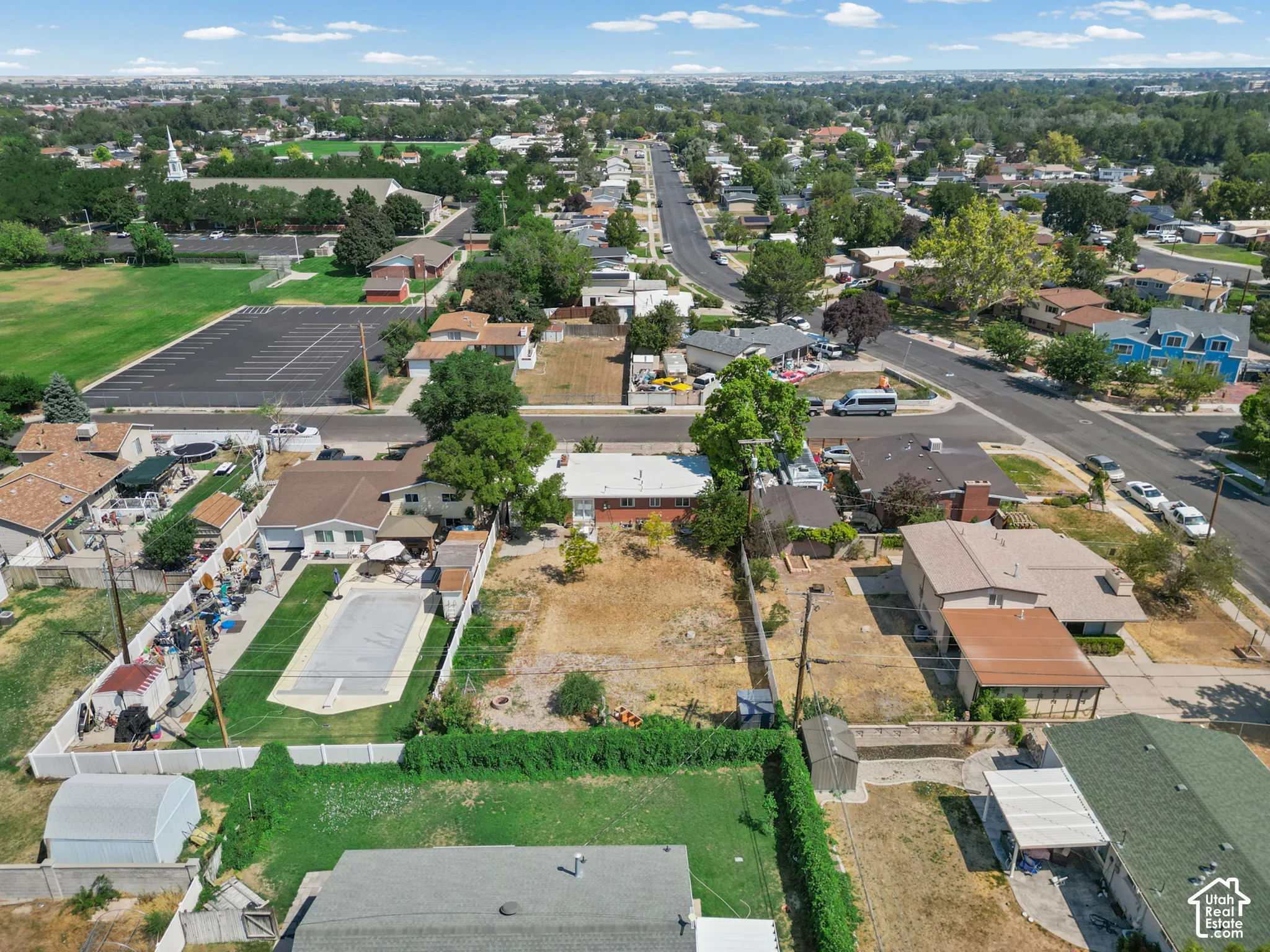 Aerial perspective featuring a rectangular lot, mature perimeter landscaping, and established residential surroundings