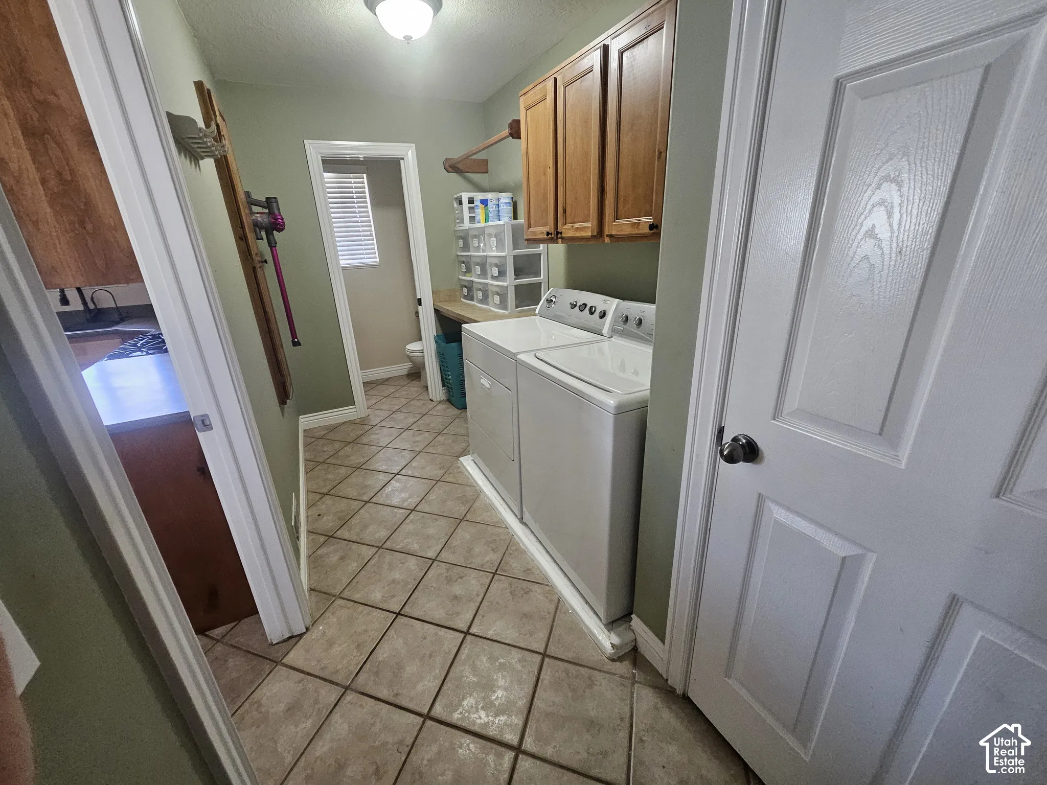 Utility area featuring diagonal ceramic tile flooring, upper wood cabinetry, a built-in counter surface, and an overhead dome light fixture