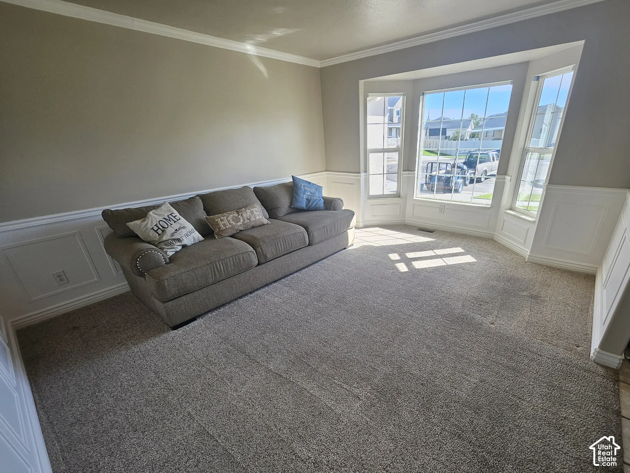 Room featuring a bay window, crown molding, and wainscoting