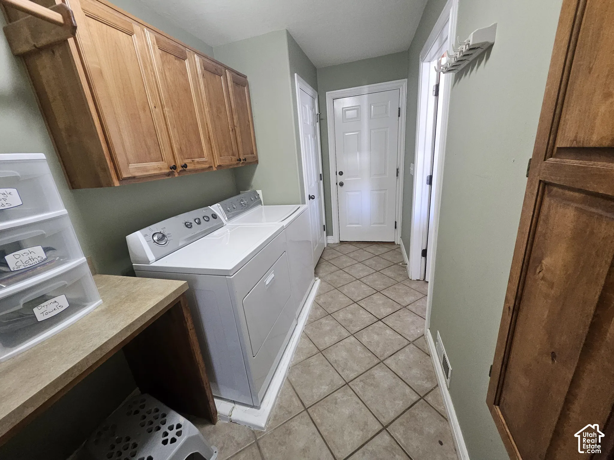 Laundry room featuring tile flooring, built-in natural wood cabinetry, and a dedicated workspace with a laminate countertop