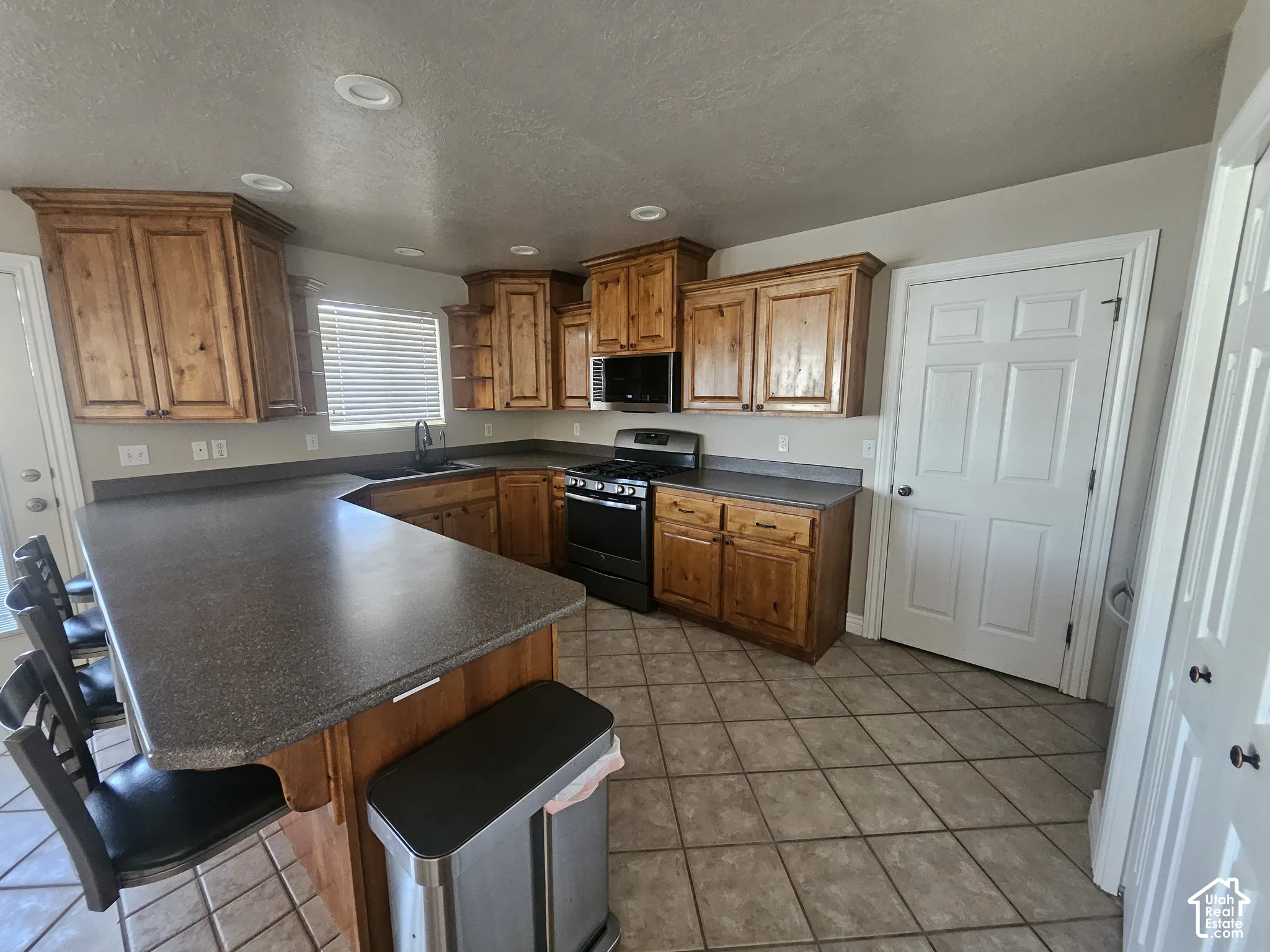 Kitchen featuring stained wood cabinetry, extended peninsula countertop, recessed lighting, and tile flooring