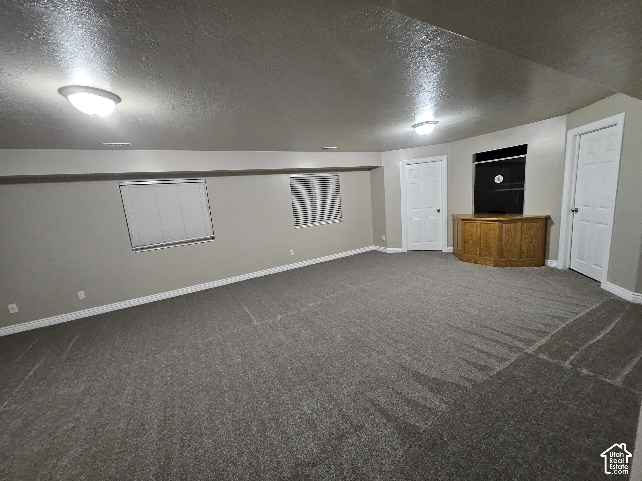 Spacious interior featuring neutral wall tones, wall-to-wall carpeting, recessed ceiling lighting, and a built-in wood cabinetry unit