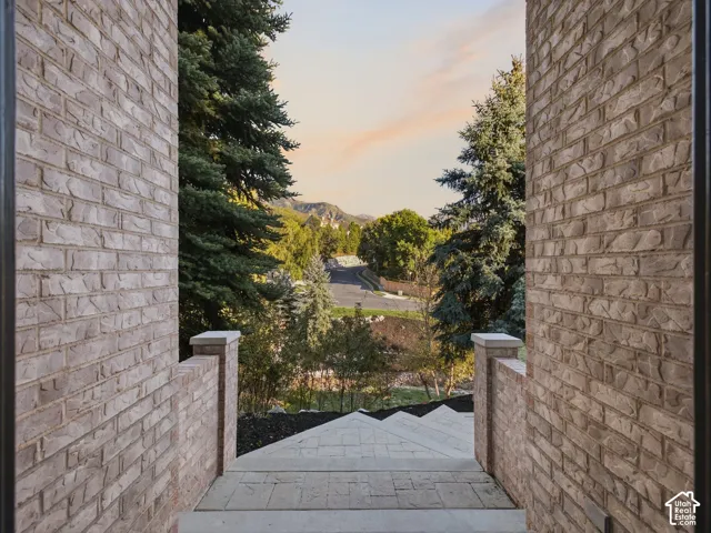 Textured brick exterior architecture, stone-paved stairway, stone-capped brick pillars, and mountainous backdrop