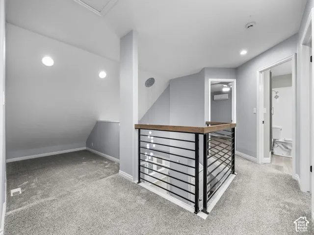 Neutral-toned carpeting, metal railing with a wood-finish cap, and integrated recessed lighting