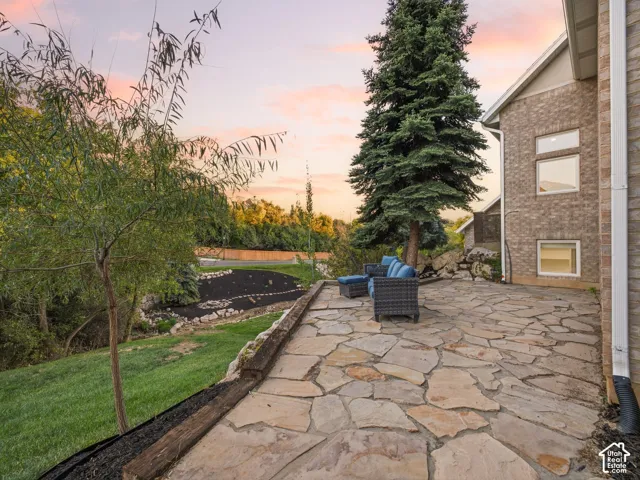 Flagstone patio featuring timber borders, masonry exterior cladding, tiered landscaping, and mature evergreen trees