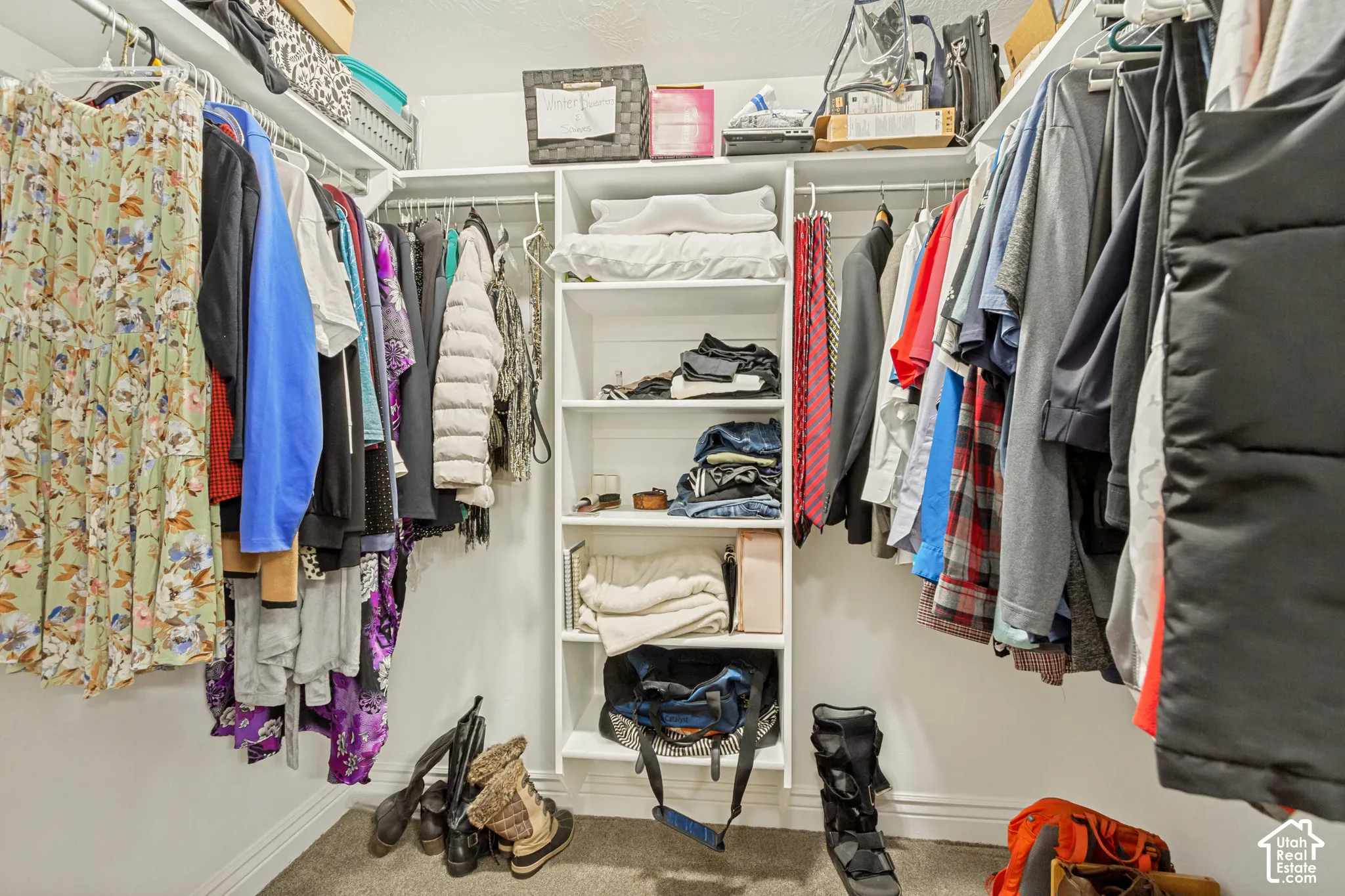 Walk-in closet featuring white built-in shelving and multi-level hanging rods