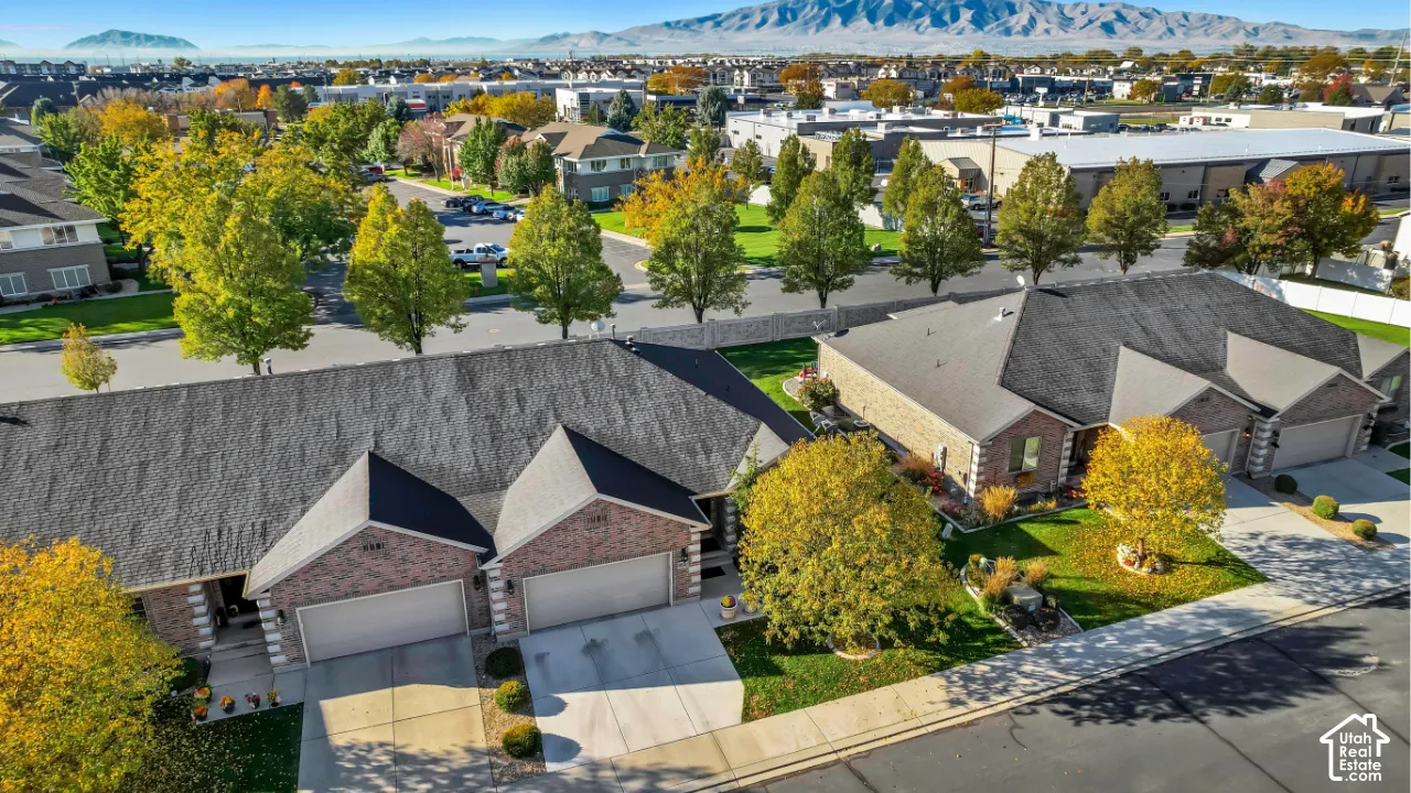Multi-unit residential complex featuring brick siding, asphalt shingle roofing, concrete driveways, and mountain-range backdrop
