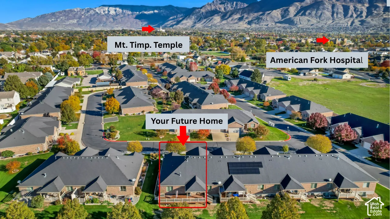Aerial perspective featuring a residential property with asphalt roof shingles, and a wood-decked patio, set against a backdrop of mountain scenery