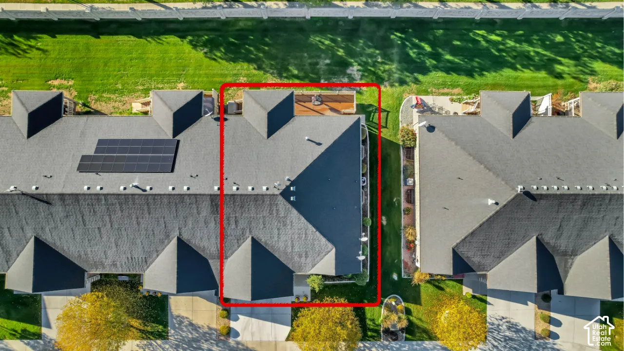 Aerial perspective of a multi-unit residential property featuring a shingled roof, attached elevated wooden deck, and concrete driveway