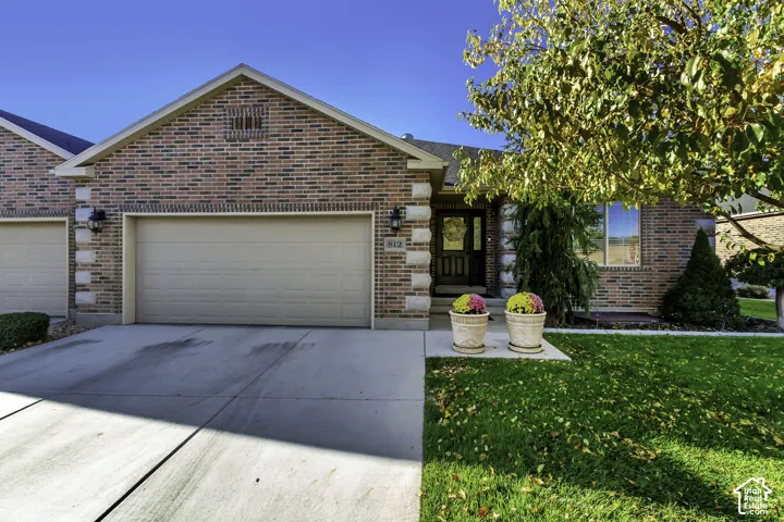 Brick exterior featuring stone corner accents, concrete driveway, and attached garage