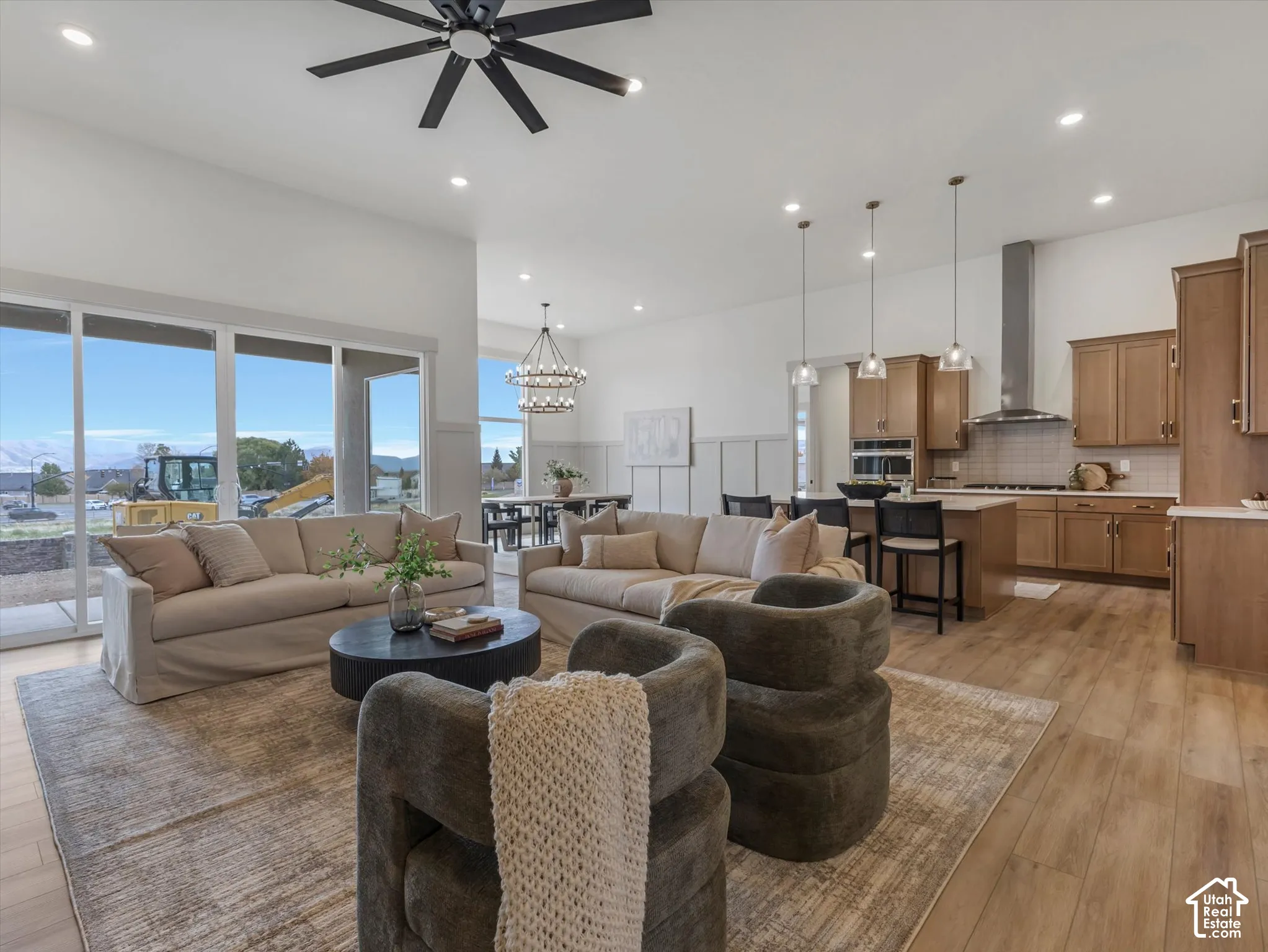 Open-concept interior featuring wood-finish flooring, high ceilings, recessed lighting, expansive glass sliding doors, and custom cabinetry with stainless steel appliances