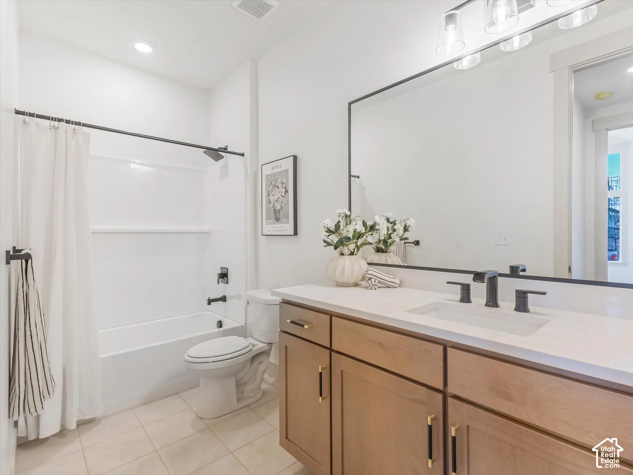 Bathroom featuring a vanity with wood-finish cabinetry, quartz countertop, rectangular undermount sink, matte black hardware, and an expansive wall-mounted mirror