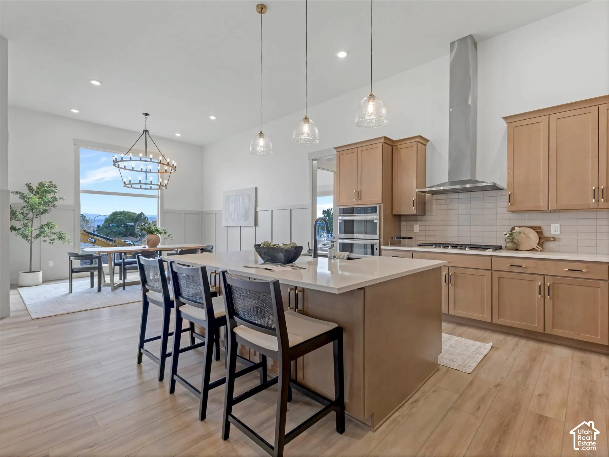 Kitchen featuring a central island with quartz countertops, custom wood cabinetry, a stainless steel chimney-style range hood, recessed lighting, and wood-finish flooring