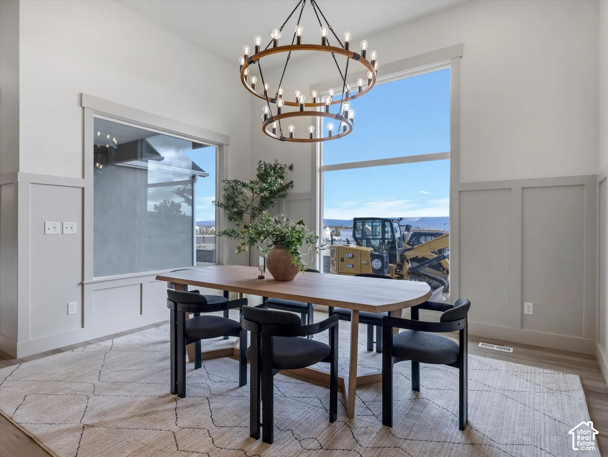 High-ceiling dining area featuring wall paneling, large windows, and a multi-tiered circular chandelier