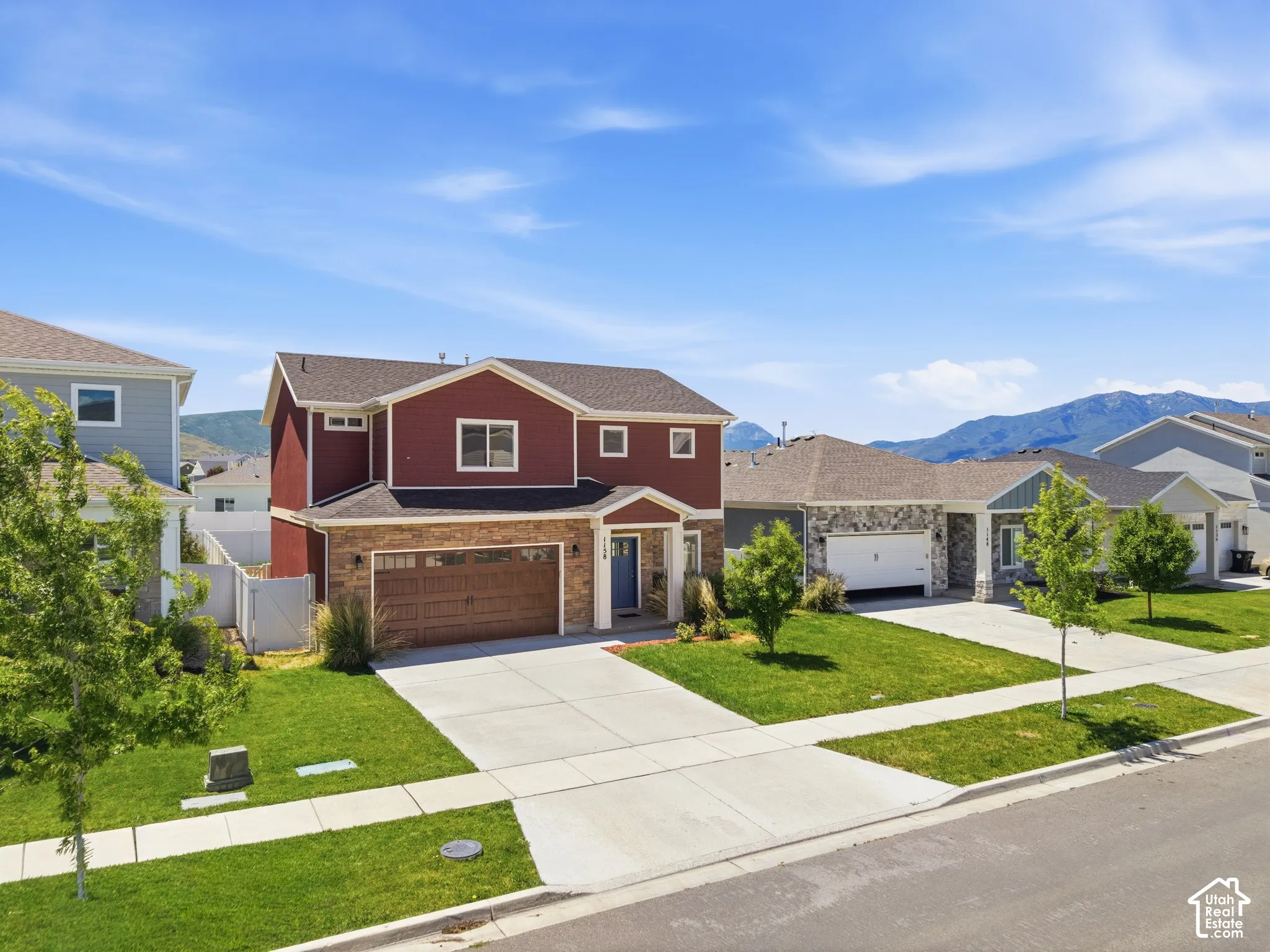 Two-story exterior featuring stone veneer siding, a front-facing attached two-car garage, and a covered entryway with mountain scenery