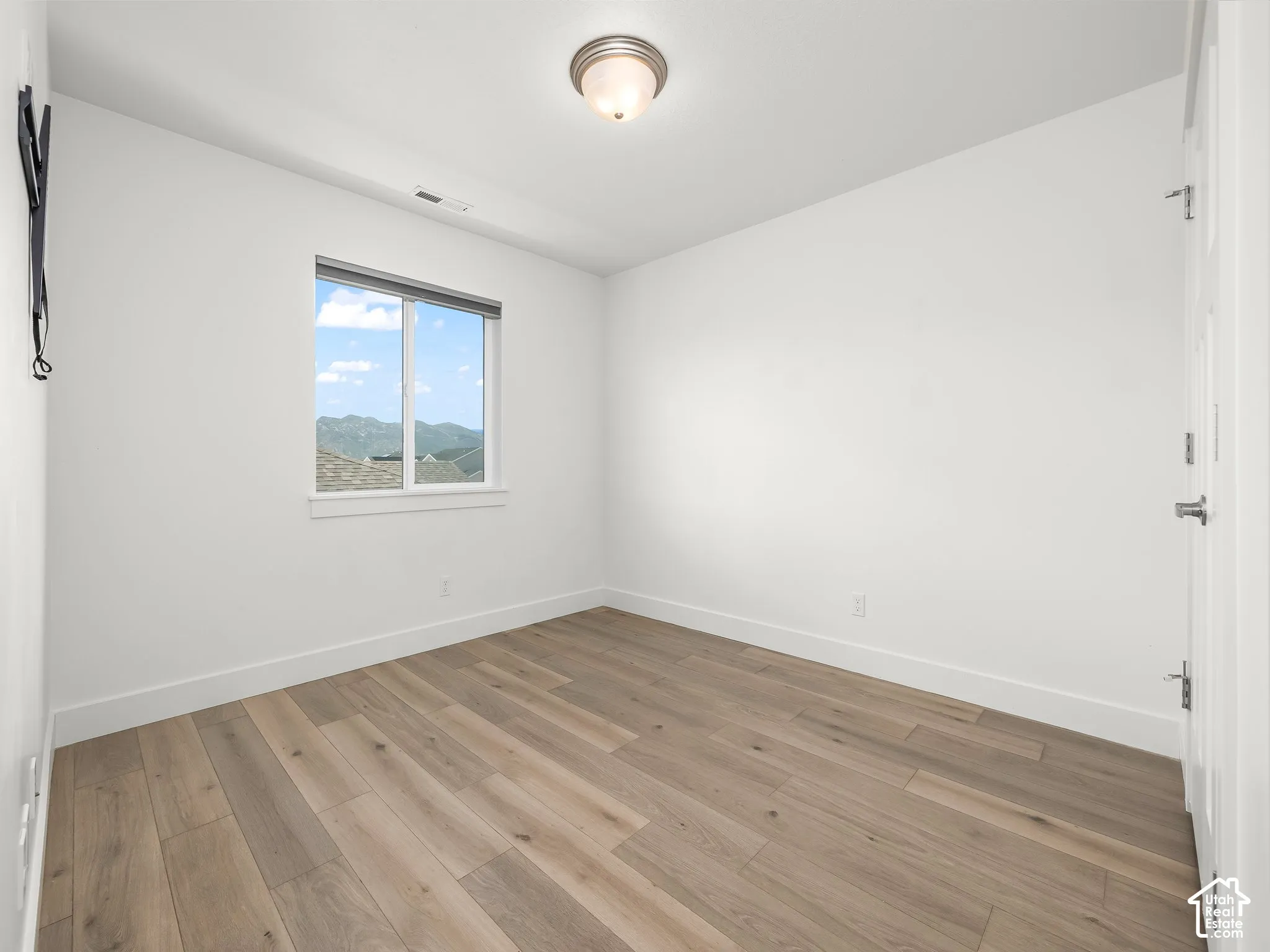 Neutral-toned wood-finish flooring, sliding window with exterior mountain scenery, and ceiling-mounted dome lighting
