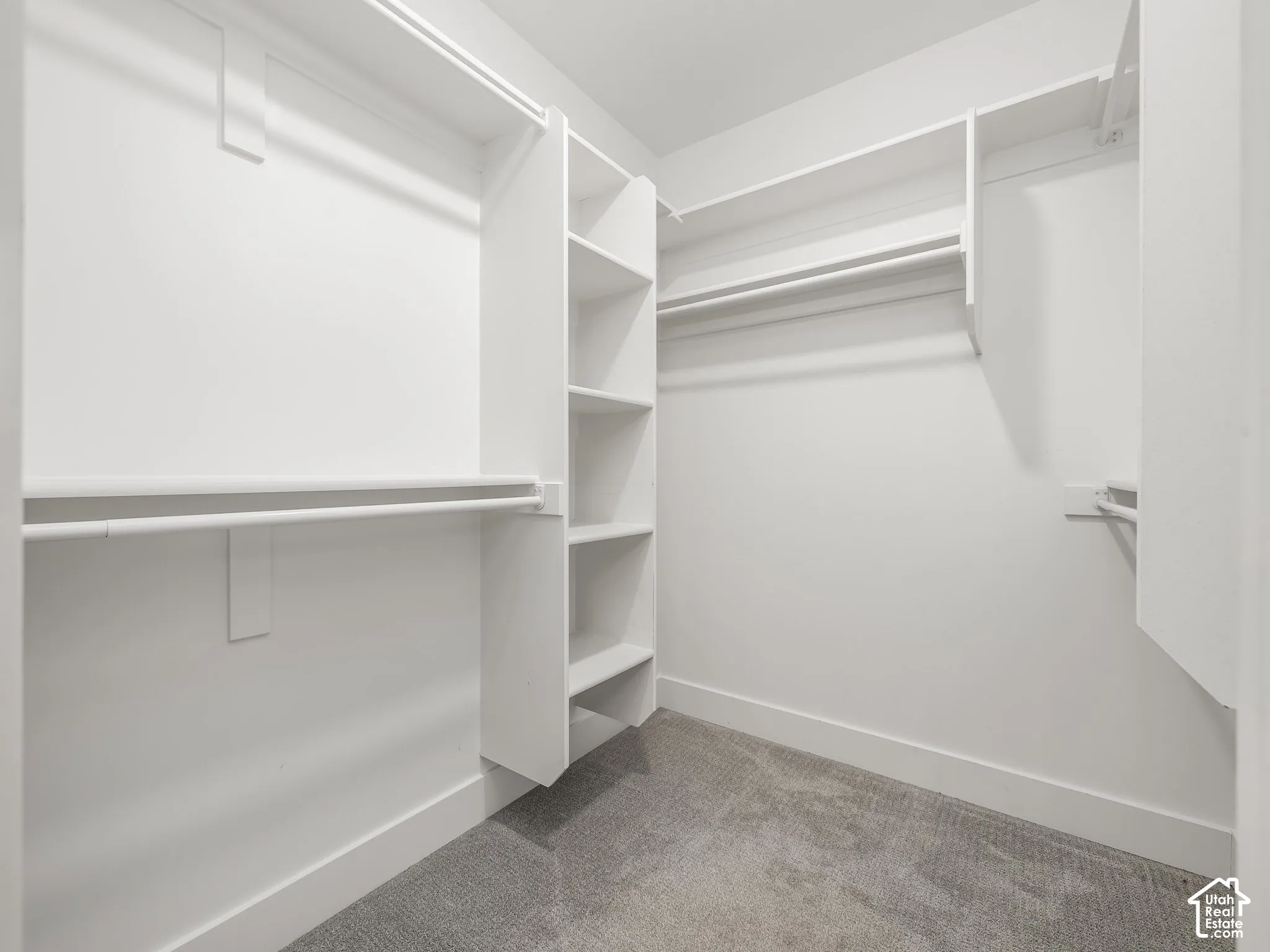 Walk-in closet featuring white built-in shelving, integrated tiered storage cubbies, and wall-to-wall carpeting