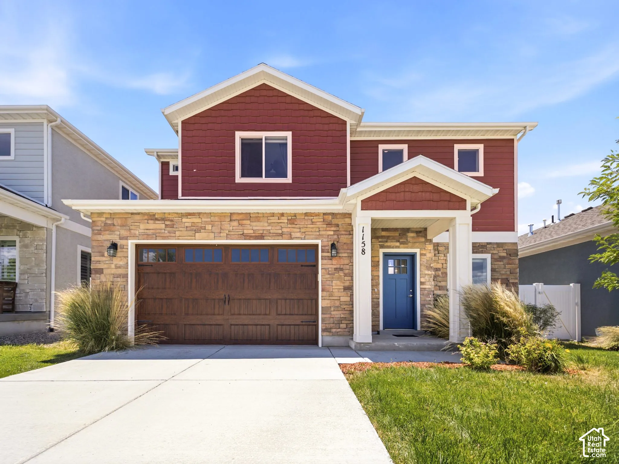 Two-story residence featuring a combination of stone veneer and horizontal siding, a multi-paneled wood-finish garage door, and a covered entryway
