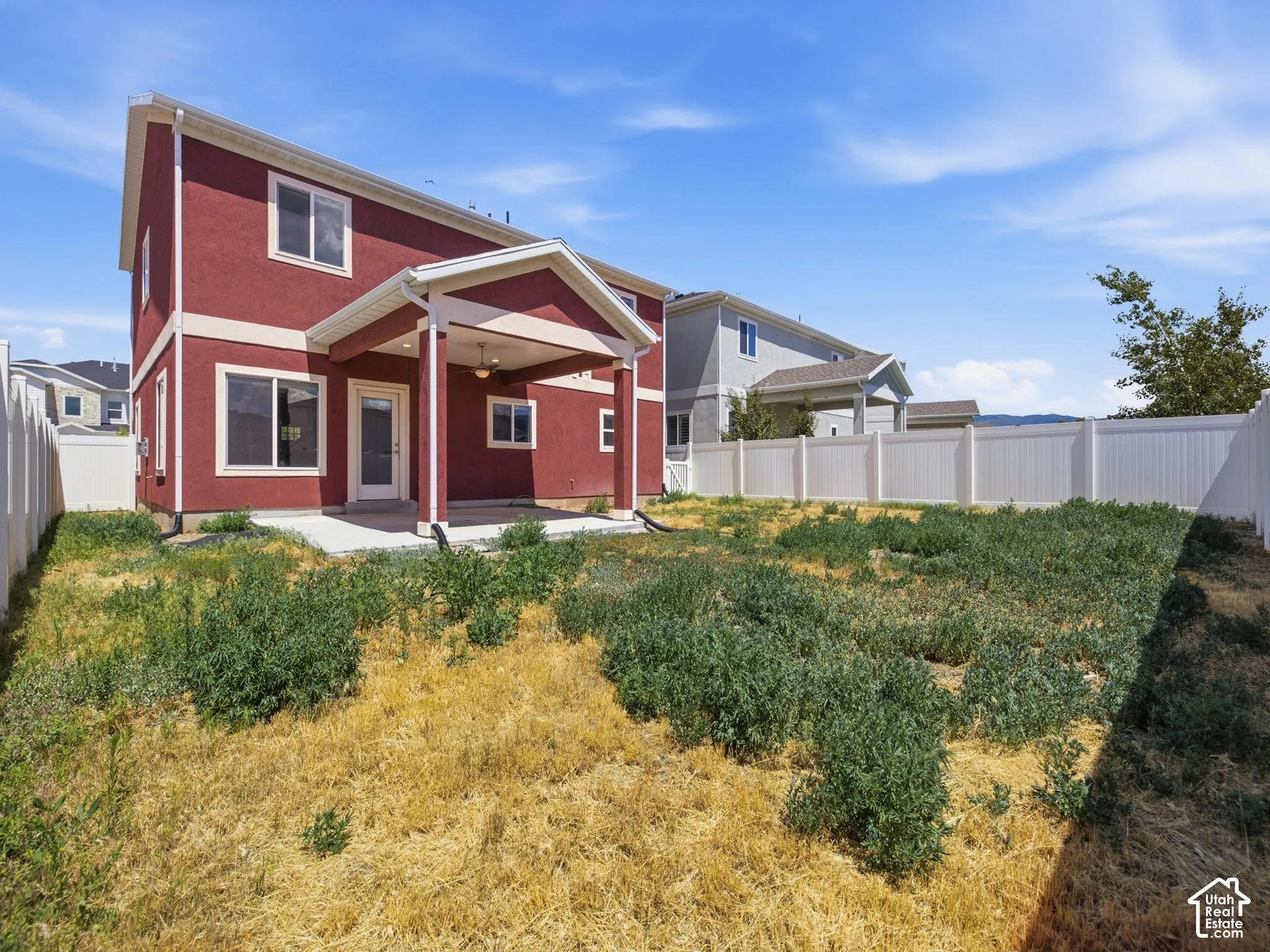 Stucco exterior featuring a covered rear patio, integrated ceiling fan, and full perimeter vinyl fencing