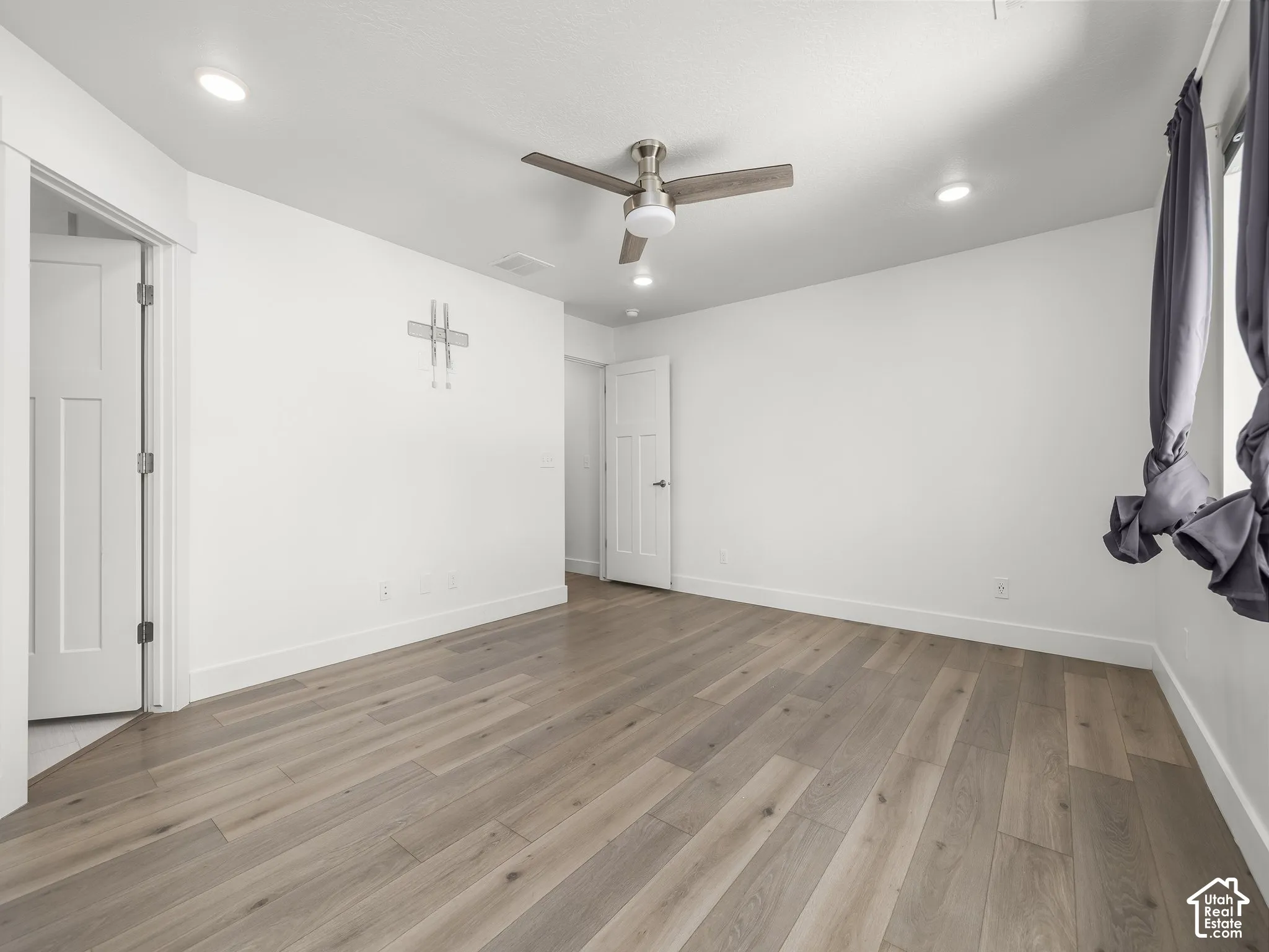 Room interior featuring wood-finish flooring, recessed lighting, and a multi-blade ceiling fan with an integrated light fixture