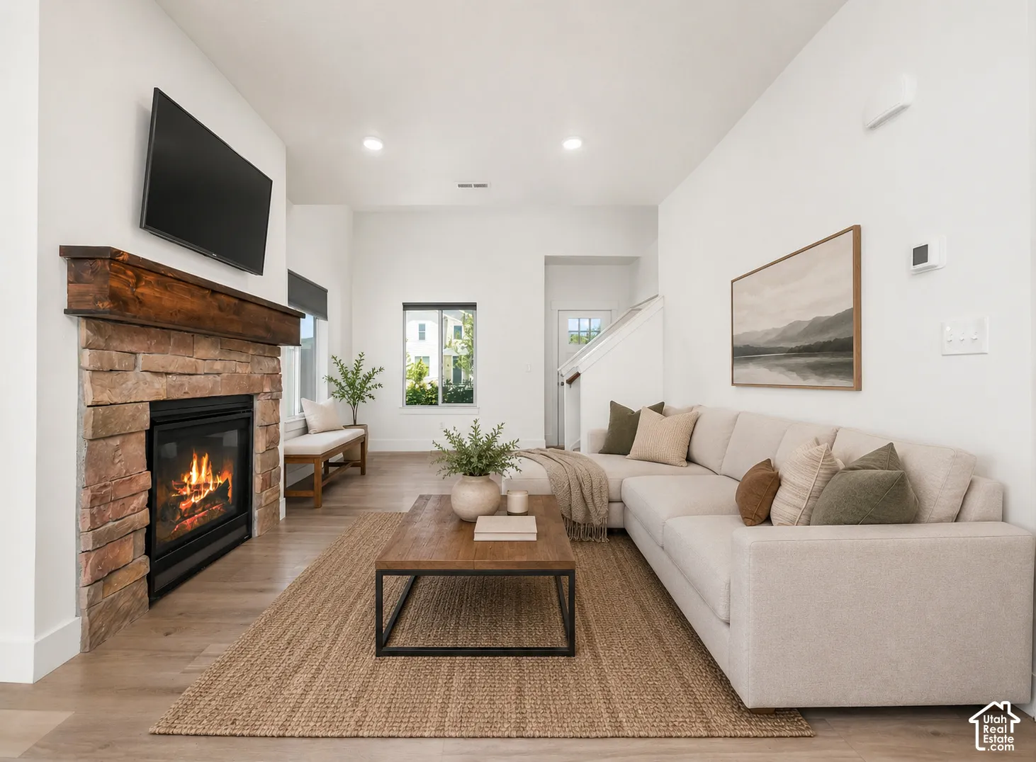 Living area featuring a floor-to-ceiling stone fireplace, a rustic wood mantel, recessed lighting, and wood-finish flooring