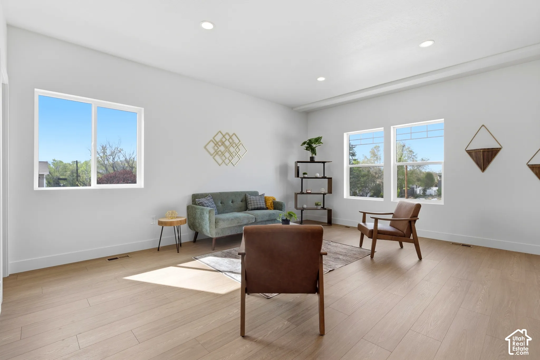 Spacious room with light wood-finish flooring, recessed lighting, and multiple windows