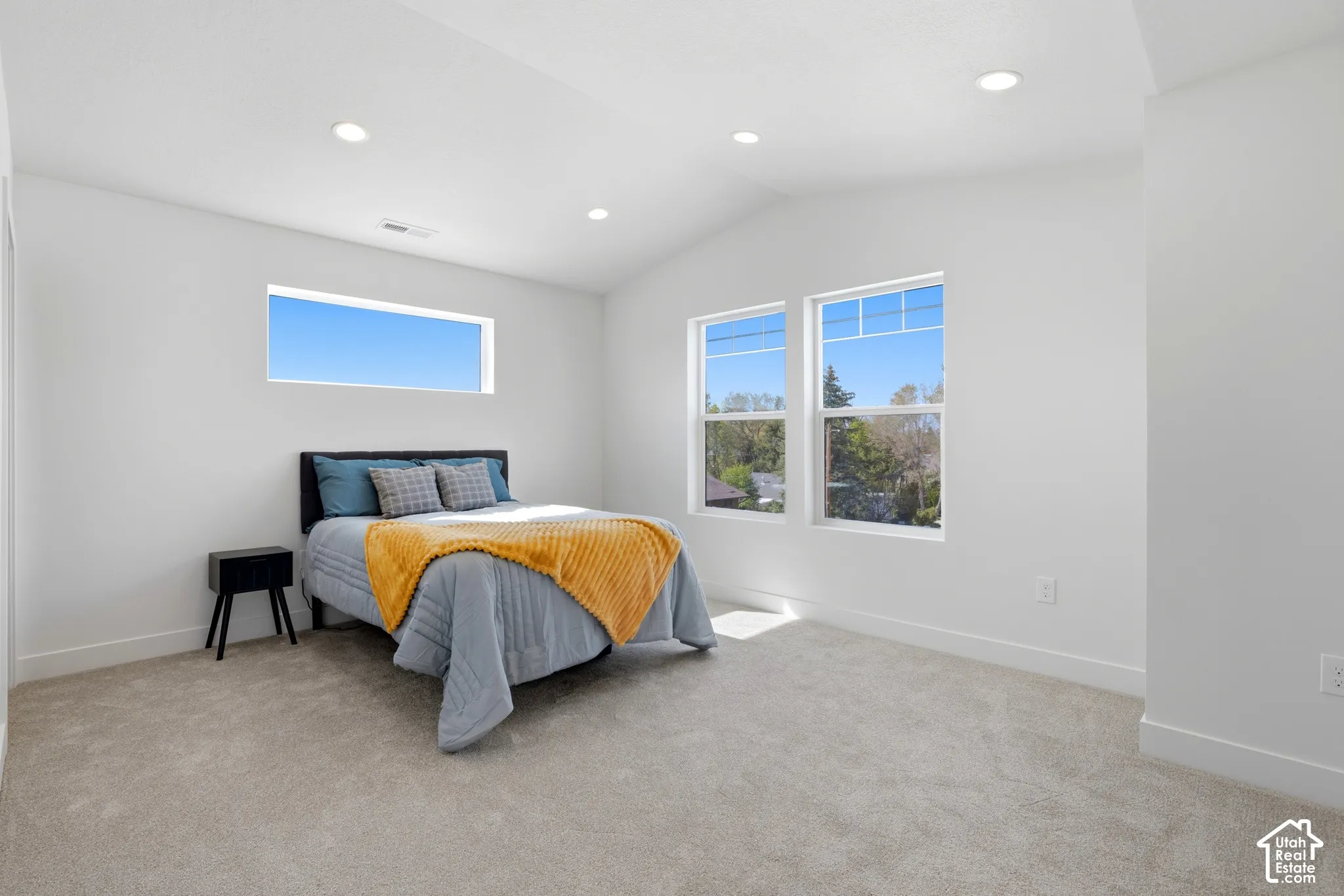 Vaulted ceiling with recessed lighting, light-toned carpeting, and multiple windows