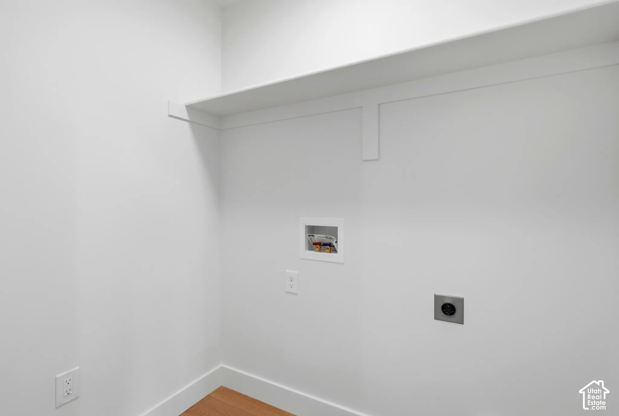 Laundry area featuring a built-in shelf, wood-finish flooring, and essential utility hookups