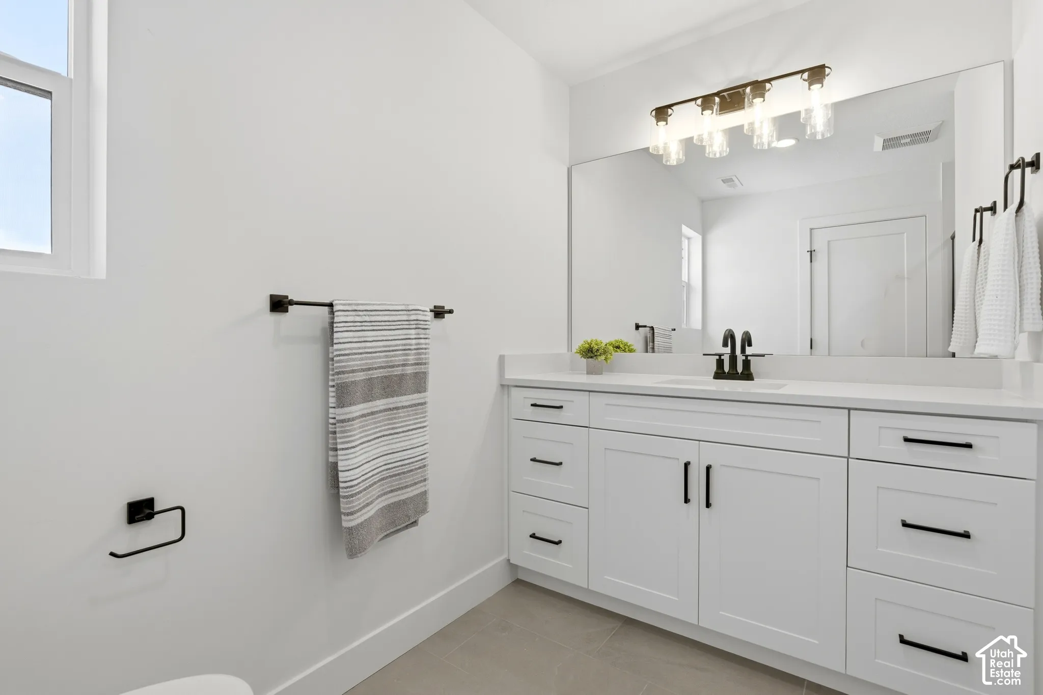 Extended vanity with white cabinetry, matte black hardware, and a single basin sink