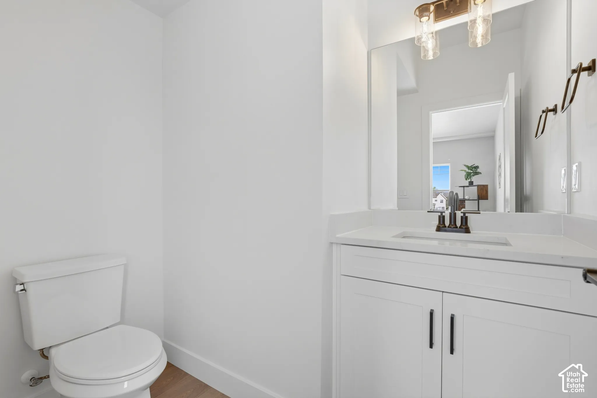 White vanity with shaker-style cabinetry, a solid surface countertop, and a rectangular undermount sink