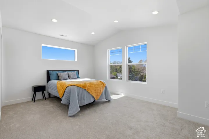 Vaulted ceiling with recessed lighting, light-toned carpeting, and multiple windows