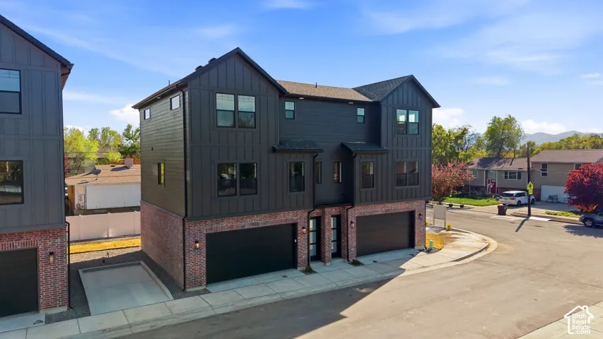 Modern architectural design featuring vertical siding, brick accents, and two integrated garages