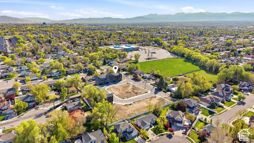 Expansive residential area with a large green space, mature trees, and distant mountains