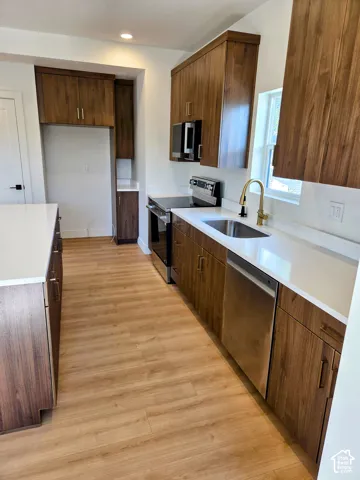 Kitchen featuring wood-finish cabinetry, quartz countertops, an island, wood-finish flooring, and stainless steel appliances