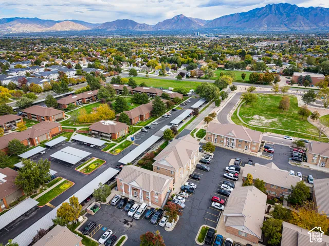 Aerial perspective of a multi-unit residential community featuring brick masonry exteriors, metal-roofed covered parking, paved driveways, and expansive mountain backdrops