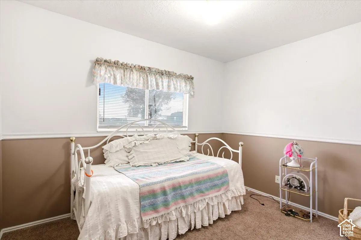 Bedroom featuring two-tone wall paint, decorative chair rail molding, and a dual-pane sliding window