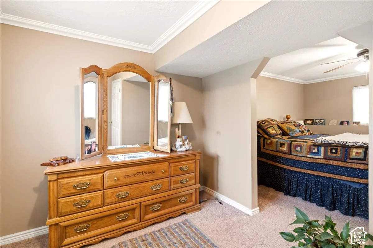 Bedroom featuring neutral wall paint, crown molding, and wall-to-wall carpeting