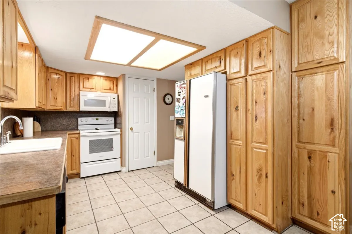 Kitchen featuring natural wood cabinetry, tiled flooring, recessed panel doors, and a flush-mount overhead lighting fixture