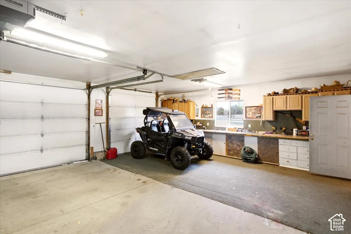 Multi-car garage featuring a concrete floor, built-in wooden cabinetry, integrated workbench, and overhead fluorescent lighting