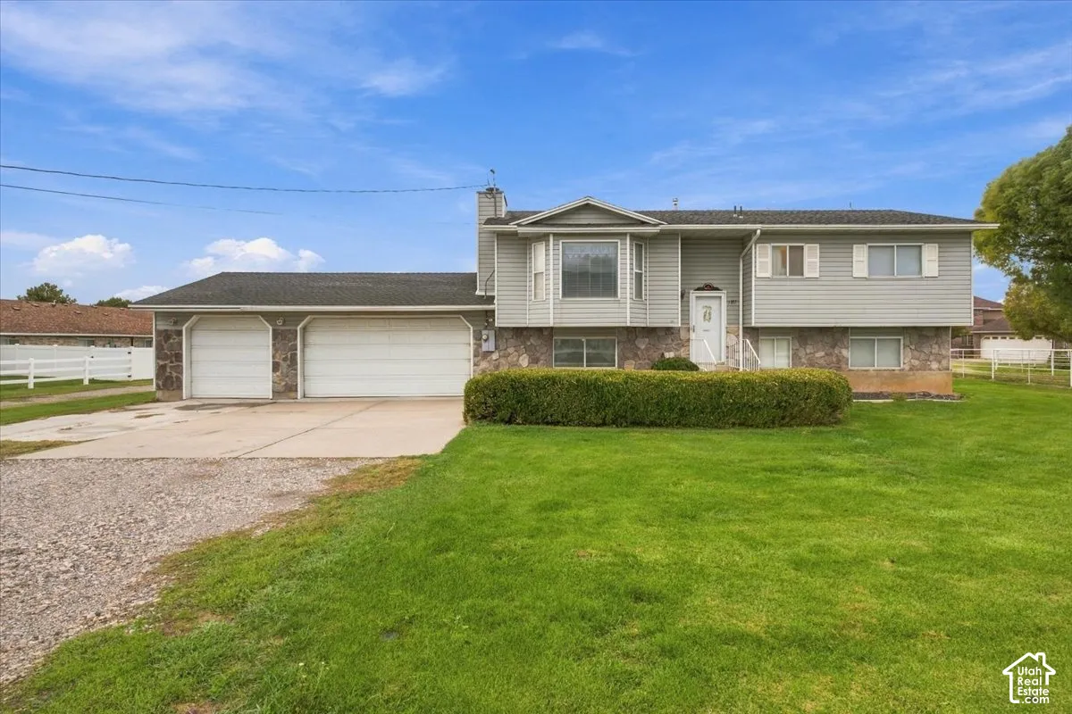 Featuring grey horizontal siding, stone veneer masonry, a two-car garage, and a bay window