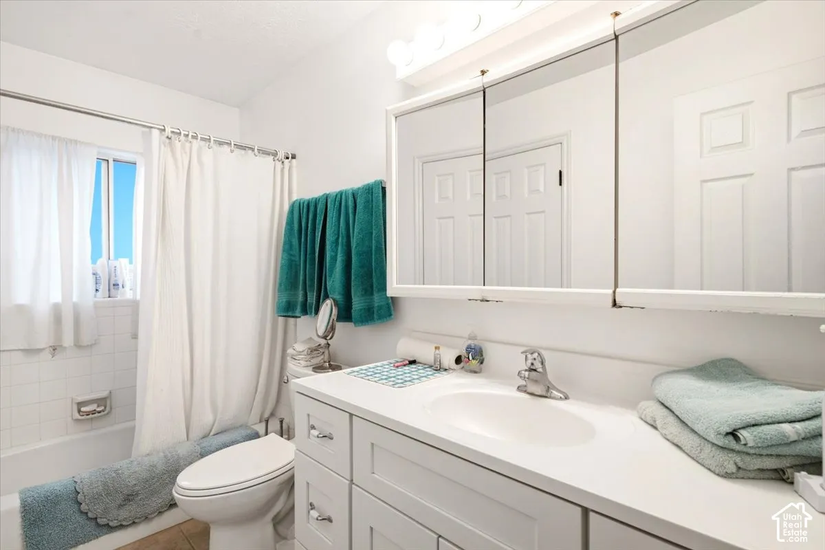 Bathroom featuring a white vanity with an integrated basin, a multi-panel mirrored medicine cabinet, and a tiled shower-tub combination